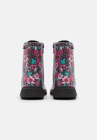 Bottines florales avec un fond noir, ornées de fleurs roses et bleu sarcelle, semelle noire robuste et fermetures éclair sur les côtés pour un enfilage facile.