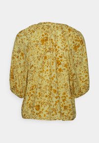 Blusa floral em amarelo claro com flores mostarda. Apresenta um decote franzido, mangas largas e um corte solto. Tecido suave e texturizado.
