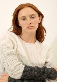 Jasno beżowy i ciemnoszary sweter z dzianiny o teksturowanym wzorze. Długie rękawy, okrągły dekolt i luźny krój. Subtelne akcenciki w całej powierzchni.