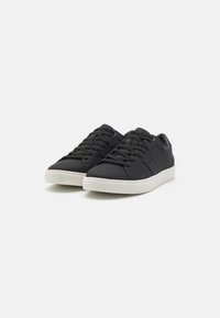 Sneakers neri con una tomaia sintetica liscia, dotati di una suola in gomma bianca, chiusura con lacci e design minimalista senza marchi visibili.
