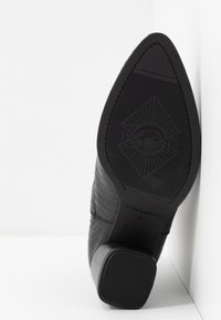 Bottine noire à bout pointu avec tige en cuir texturé, talon bloc et semelle à motif marquée "VAGABOND 37".
