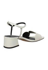 Sandali con tacco a blocco in pelle bianca, dotati di cinturino alla caviglia regolabile e design open toe. Foderati in nero e con suola texturizzata.