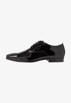 Black patent leather dress shoe with a pointed toe, five eyelets, and minimalistic design, featuring a rubber sole and subtle brand logo.