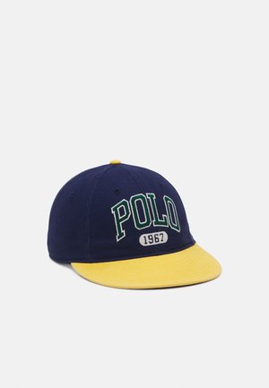 Marineblå baseballkasket med gul skygge, med "POLO" i store grønne bogstaver og "1967" broderet foran.