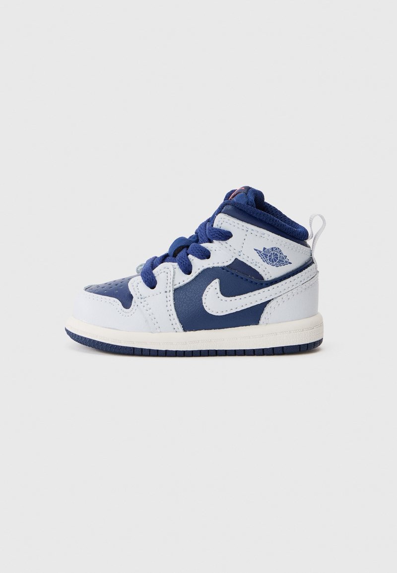 Baskets Nike Air Jordan bébé blanches et bleu marine avec lacets et languette, sur fond clair uni.