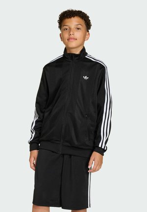 Black zip-up track jacket with white Adidas logo and three white stripes on sleeves, paired with black shorts. Smooth, lightweight fabric.