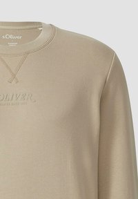 Béžová bavlnená mikina s okrúhlym výstrihom a rebrovanými manžetami, s vypáleným názvom značky "s.Oliver" na prednej strane. Hladká textura.