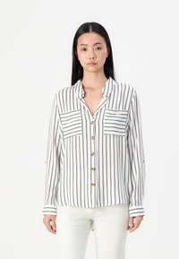 White button-up shirt with vertical black stripes, two chest pockets, and a collar. Long sleeves feature striped cuffs.