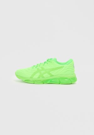 Green athletic shoes with a textured upper, laces, and translucent sole. Features distinctive branding on the heel and side.