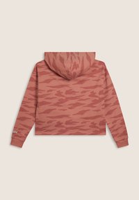 Vista posteriore di un hoodie cropped in camouflage rosa polveroso e rosso con maniche lunghe e cappuccio, adagiato su uno sfondo beige.