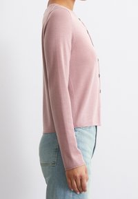 Cardigan rose pâle à manches longues en maille douce, avec un col rond, des boutons et une coupe courte à la taille.