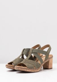 Oliivivihreät mokkanahkaiset avonaiset sandaalit, joissa on elastiset hihnat, punottu reunus, pehmeät korkkipohja-korkokengät ja kumipohjat.