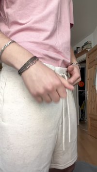 Pantaloni corti di un colore chiaro, in tessuto morbido, con chiusura a cordoncino e tasche laterali. Il materiale sembra avere una texture e un aspetto leggermente felpato.