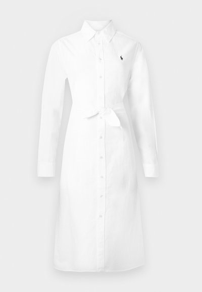 Rochie lungă albă cu nasturi, mâneci lungi, guler, cordon în talie și un mic logo închis la culoare pe pieptul stâng.