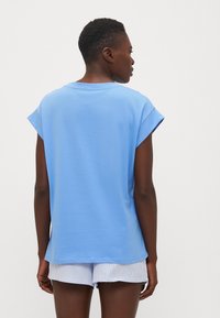 Lichtblauw T-shirt met korte mouwen, relaxed fit, ronde hals en zachte katoenen stof, gecombineerd met gestreepte shorts.