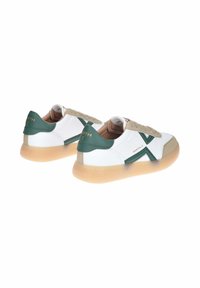 Sneaker bianche con accenti verde e beige, tomaia in pelle liscia, linguetta testurizzata e suola in gomma traslucida con motivo sottile.