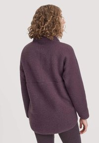 Fleece pullover syvällä violetilla, jossa on korkea kaulus ja rento istuvuus. Teksturoitu pinta ja takasauman yksityiskohdat parantavat muotoilua.