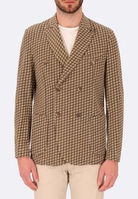 Blazer doppiopetto in motivo houndstooth marrone con due bottoni, rever a punta e tasche laterali. Realizzato in tessuto testurizzato.