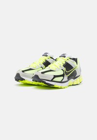 Nike löparskor med en grå mesh-ovandel, svarta detaljer, ljusgula inslag och en strukturerad sula för bra grepp.