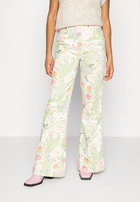 Pantalones acampanados con estampado floral en crema claro con patrones botánicos en verde, rosa y azul. Cuentan con una cinturilla y un ajuste ceñido en la cintura.