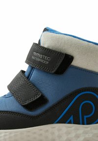 Wodoodobny but dziecięcy z ciemnoniebieskiej tkaniny, z czarnymi akcentami, dwoma czarnymi paskami na rzep oraz teksturowaną podeszwą z geometrycznym wzorem.