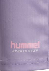 Hummel sportkläder i ljuslila tyg har en slät textur med en tryckt logotyp i rosa och vitt nertill.