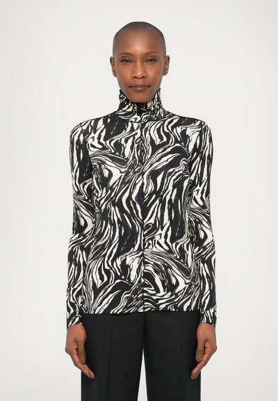 Black and white long-sleeve top with a high neckline and abstract wave pattern; made from a smooth fabric with a fitted design.