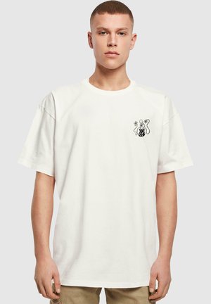 White cotton t-shirt with short sleeves, featuring a black graphic design on the left chest, with abstract shapes and floral accents.