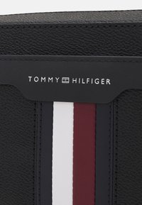 Portafoglio in pelle nera con superficie testurizzata, caratterizzato da strisce verticali nei colori: rosso, bianco e blu navy. Logo in argento nella parte superiore.