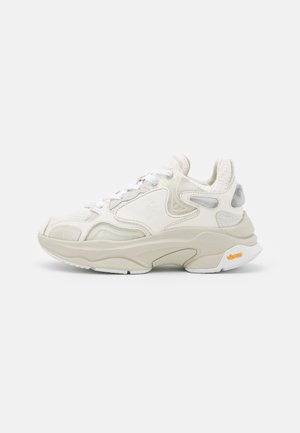 Witte en beige chunky sneaker met mesh- en leren details, witte veters en een dikke zool met een geel Vibram-logo.