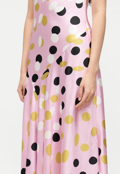 Rózsaszín szatén ruha fekete, fehér és arany körmintákkal. Laza, folyékony szabású és aszimmetrikus vágású, kiemelve a redők textúráját.