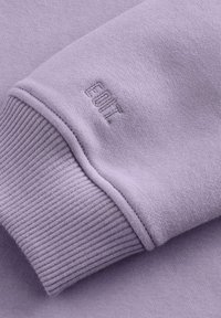 Lichtpaars sweatshirtstof met geribde manchetten, voorzien van een subtiele geborduurde "EDIT" logo. Glad textuur met een relaxte pasvorm en strakke lijnen.