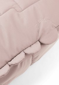 Pohodlná deka z měkké růžové tkaniny s prošívaným vzorem; má zakřivené okraje a jemnou výšivku slunce v světlé niti.