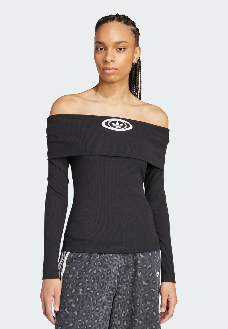 Svart off-the-shoulder topp med lange ermer og ribbet tekstur. Har et sentralt hvitt logo med ovalt design. Parret med leopardmønstrede bukser.
