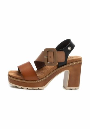 Sandalias de tacón alto de cuero marrón con tiras anchas, detalle de hebilla y parte trasera negra texturizada. Suela de plataforma con un borde blanco estriado.