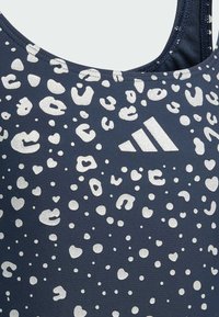 Maillot de bain navy avec un motif de taches de léopard blanches et de cœurs, avec une finition texturée ; comprend un logo Adidas en blanc.