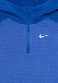 Hoodie bleu avec un design à demi-zip, tissu texturé et un petit logo Nike blanc sur la poitrine. Inclut une capuche structurée.