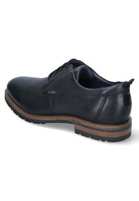 Chaussure habillée en cuir noir avec un bout rond, un laçage, une semelle brun contrastante et de subtils détails de couture sur les côtés.