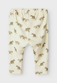 Katoenen babyleggings met een elastische tailleband. Crème achtergronden met een bruine luipaardprint. Geribbelde textuur, taps toelopend ontwerp van de pijpen.