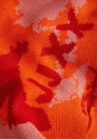 Knitted fabric featuring an abstract pattern in orange, red, and pink tones. Texture is soft with a slight stretch, showcasing a layered design.