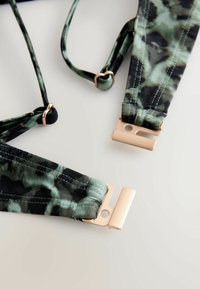 Riidepatrooniga traksid, mis on valmistatud kangast, reguleeritavate rihmade ja kuldses toonis metallkinnitusdetailidega, esile tõstetud tugevdatud õmblustega.