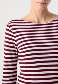 Langermet stripete skjorte med bred båtutringning. Laget av mykt stoff, med vekslende maroon og hvite horisontale striper.