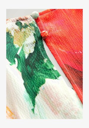 Tessuto con motivi floreali vivaci in verde, rosso e rosa; presenta bottoni decorativi nei colori corrispondenti; bordi cuciti.