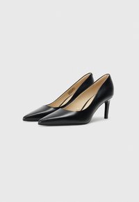 Tacones altos de cuero negro con punta afilada y tacón de aguja. El diseño presenta una textura suave y un estilo minimalista.