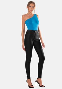 Blå one-shoulder bodysuit parat med högmidjade svarta skinny jeans och svarta remsandaler med hög klack. Slät textur, figurnära design.