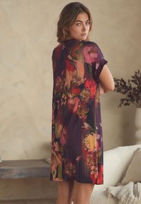 Luchtige, doorzichtige jurk in dieppaars met levendige bloemenprint, voorzien van korte mouwen, een ontspannen pasvorm en een knielengte.