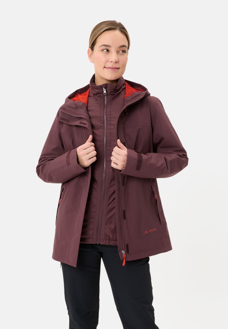 Giacca impermeabile bordeaux con cappuccio, dotata di fodera rossa, due tasche frontali e polsini regolabili. Realizzata in un tessuto liscio e resistente.
