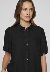 Black short-sleeved shirt with a button-down front, soft fabric, relaxed fit, and a classic collar. Subtle sheen and dark buttons.