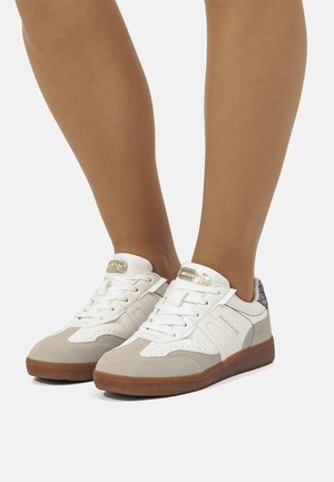 Sneakers bianchi e grigio chiaro con accenti in suede, design con lacci, colletto imbottito e suola in gomma testurizzata. Presentano un'etichetta con logo metallico.