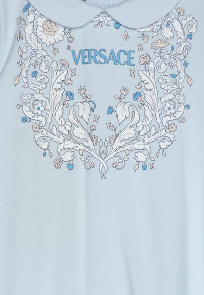 Svijetloplavi pamučni odjevni predmet s bijelim ovratnikom i ukrašenim cvjetnim uzorcima u plavim i bež nijansama. "VERSACE" je otisnut u plavoj boji.
